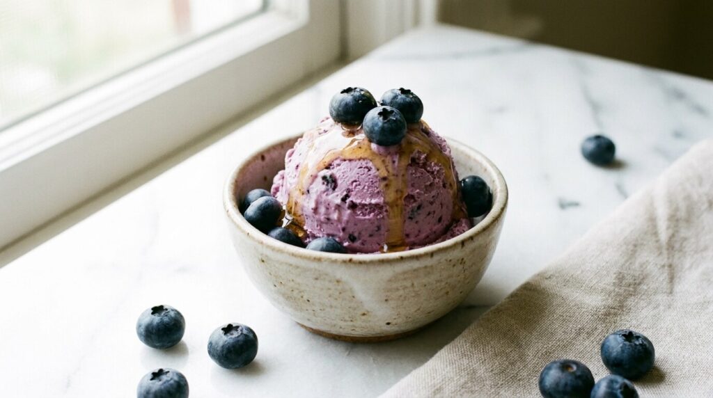 Creamy blueberry cottage cheese ice cream in a bowl topped with fresh blueberries and a honey drizzle