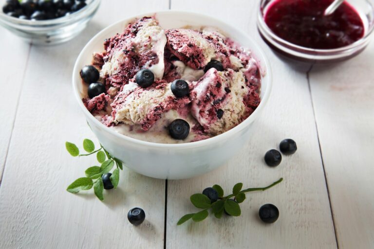 Bowl of blueberry swirl ice cream with fresh blueberries