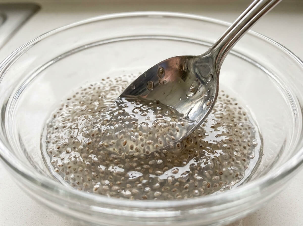Close-up of thick gelled chia seed water stirred with a spoon, showing the tapioca-like texture