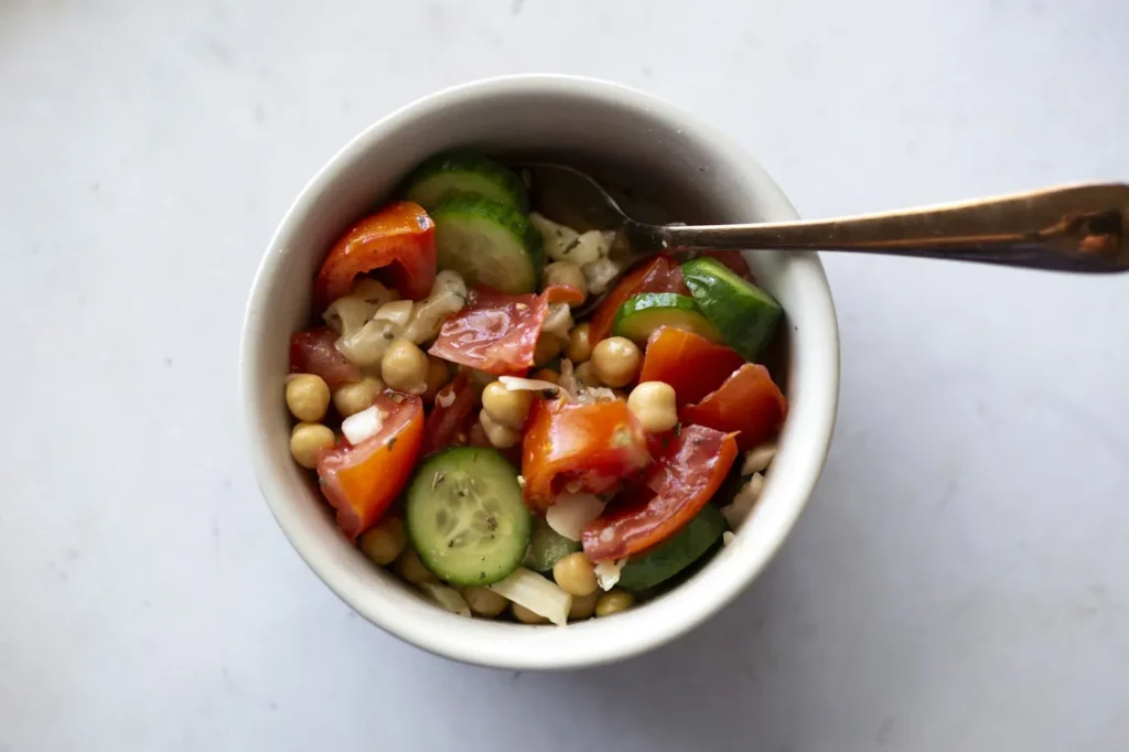 Chickpea salad with cucumber and cherry tomatoes in a white bowl