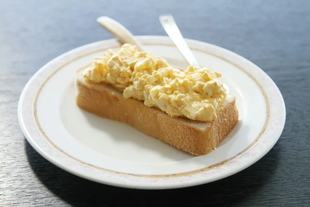 Creamy scrambled eggs piled on a thick slice of toast on a white plate
