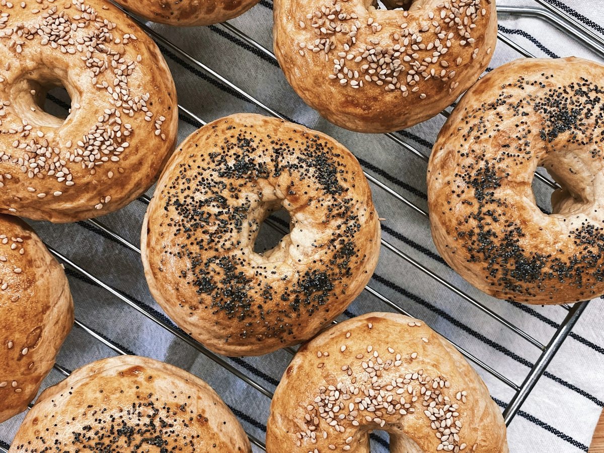 Homemade everything bagels cooling on a metal tray